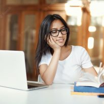 smiling female student skimming through study book while working her bachelor diploma open space library 197531 30684